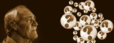 Alter Mann, der auf Kugeln mit Fragezeichen schaut