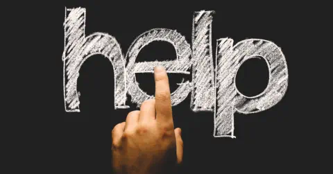 Eine Hand, deren Finger auf den Schriftzug Help tippen.